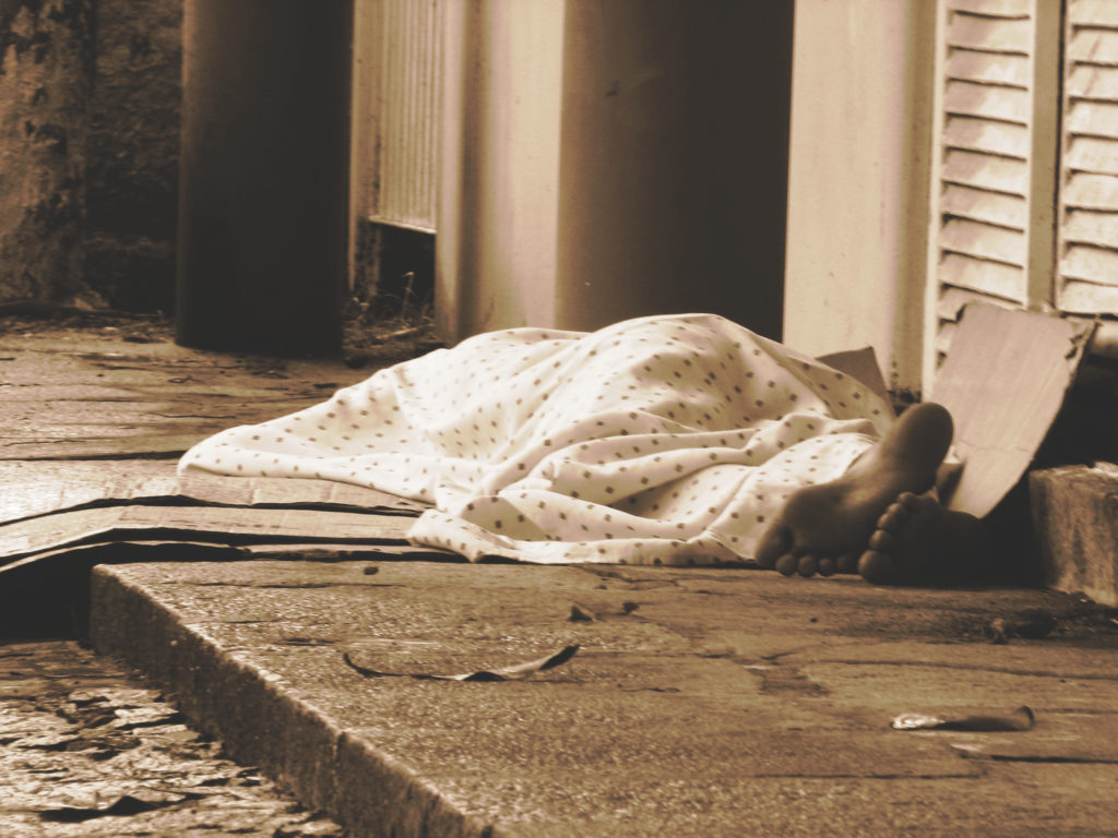 Photo of someone sleeping on wet pavement.