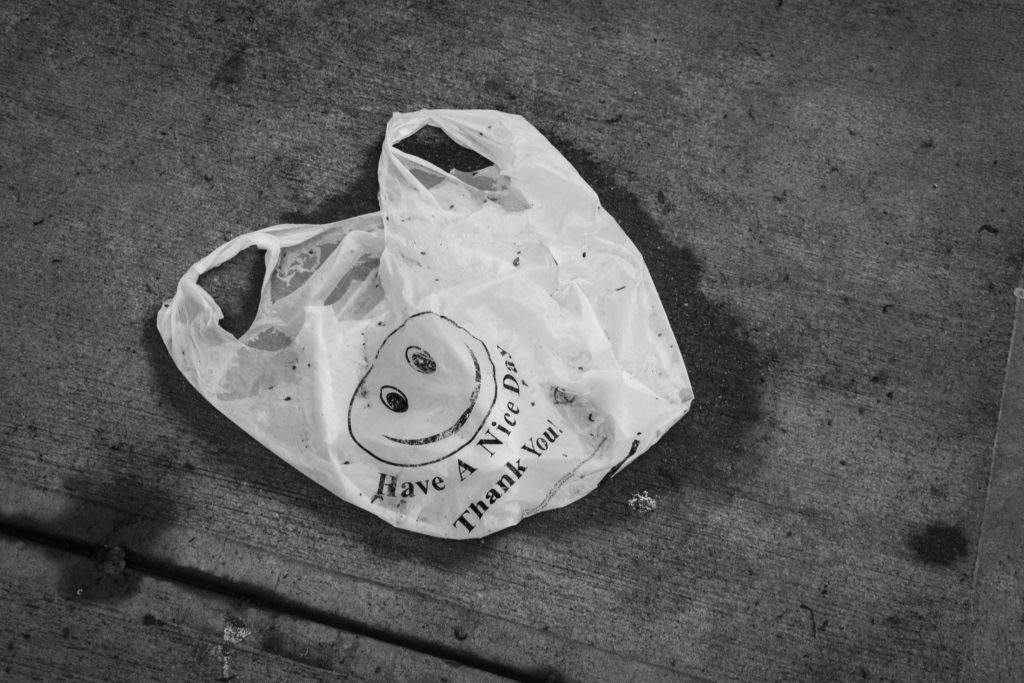 Black and white photo a dirty plastic bag with a smiley face and "Have a Nice Day Thank You!" on it.