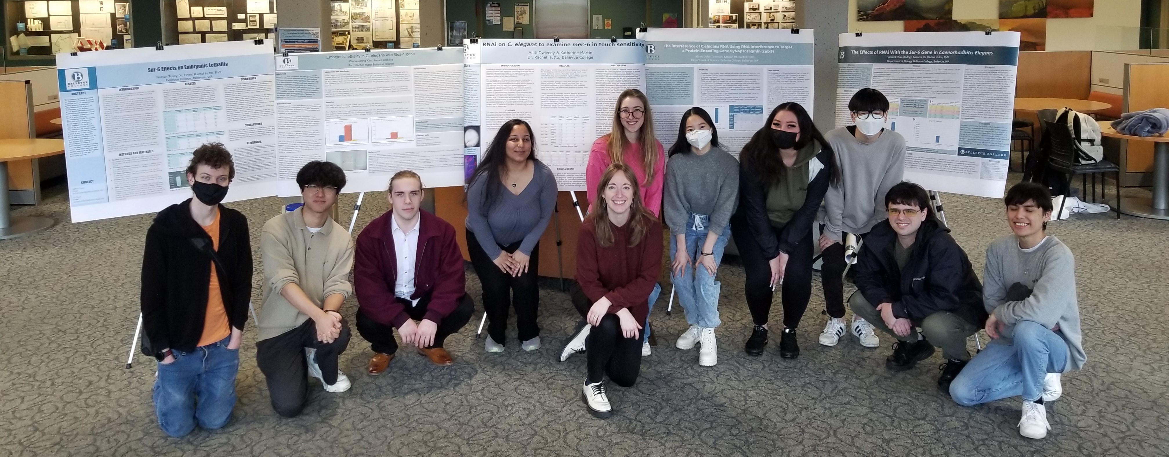 Group of people kneeling in front of research posters