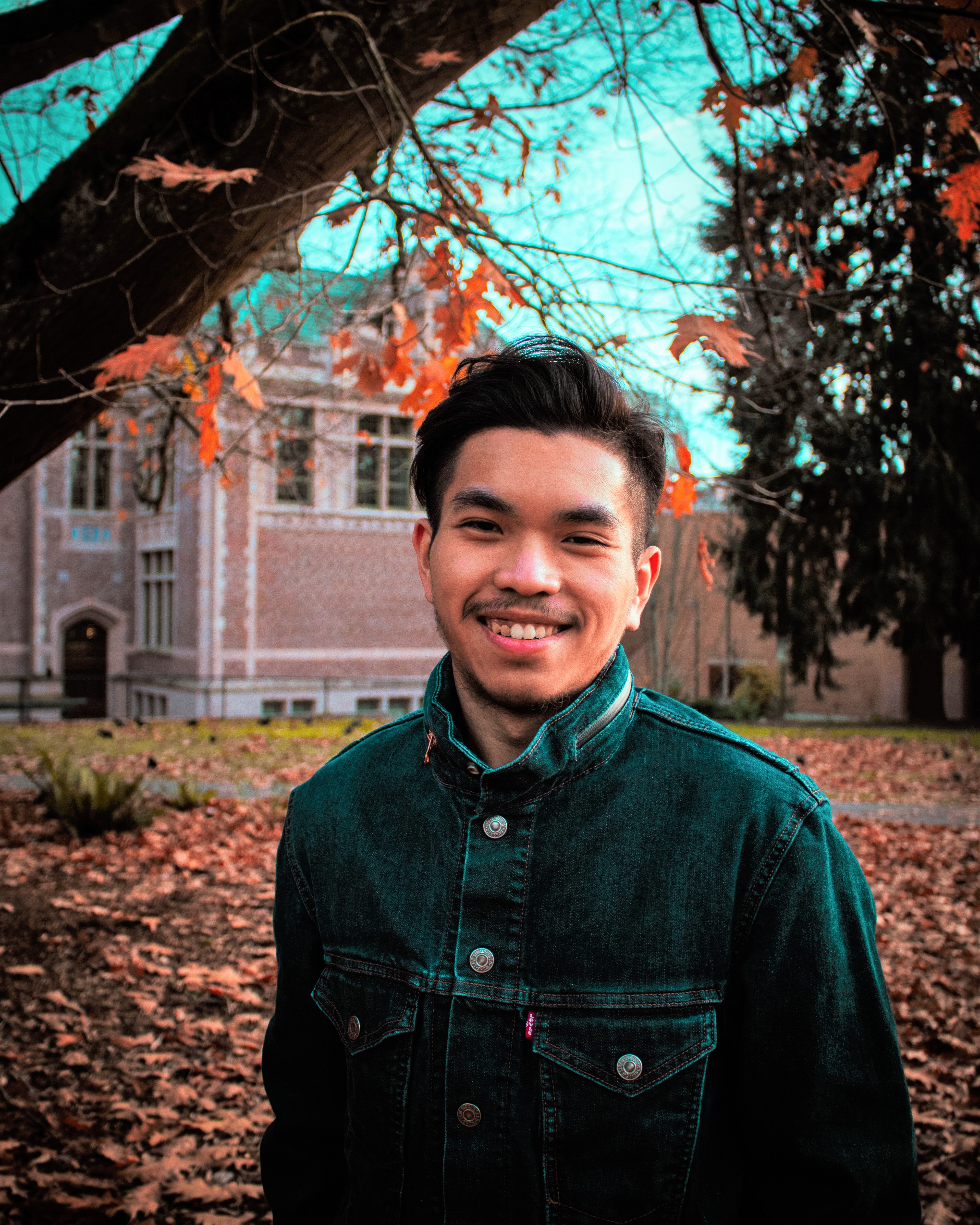 Photo of Daniel in front of brick building with leaves on the ground