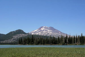 Photograph of a mountain behind a lake and open meadow.