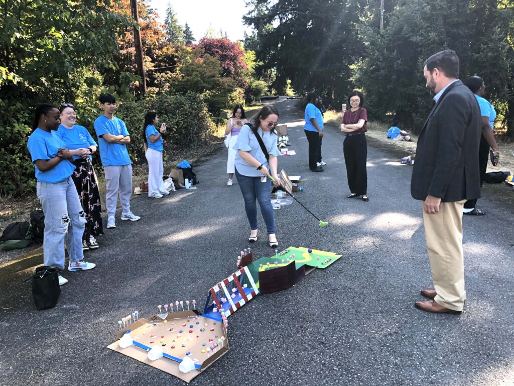 BC's President May looking on as students try out the PAW Putt golf stations.