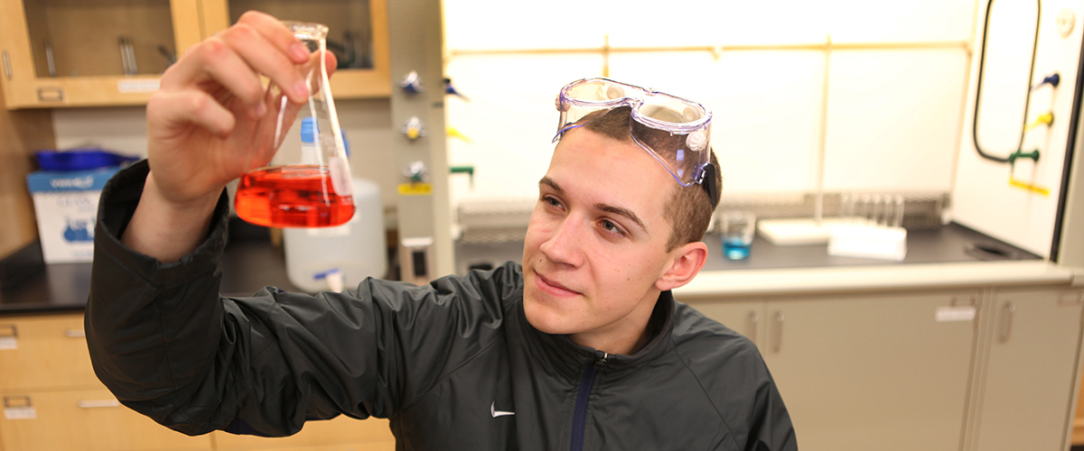 Brooks Hanson, baseball player and pre-med student, holds up a beaker in a science lab