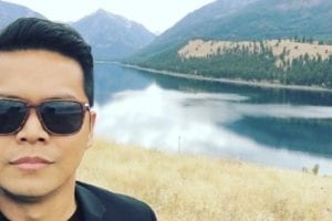 Daniel Cruz poses in front of mountains and a lake