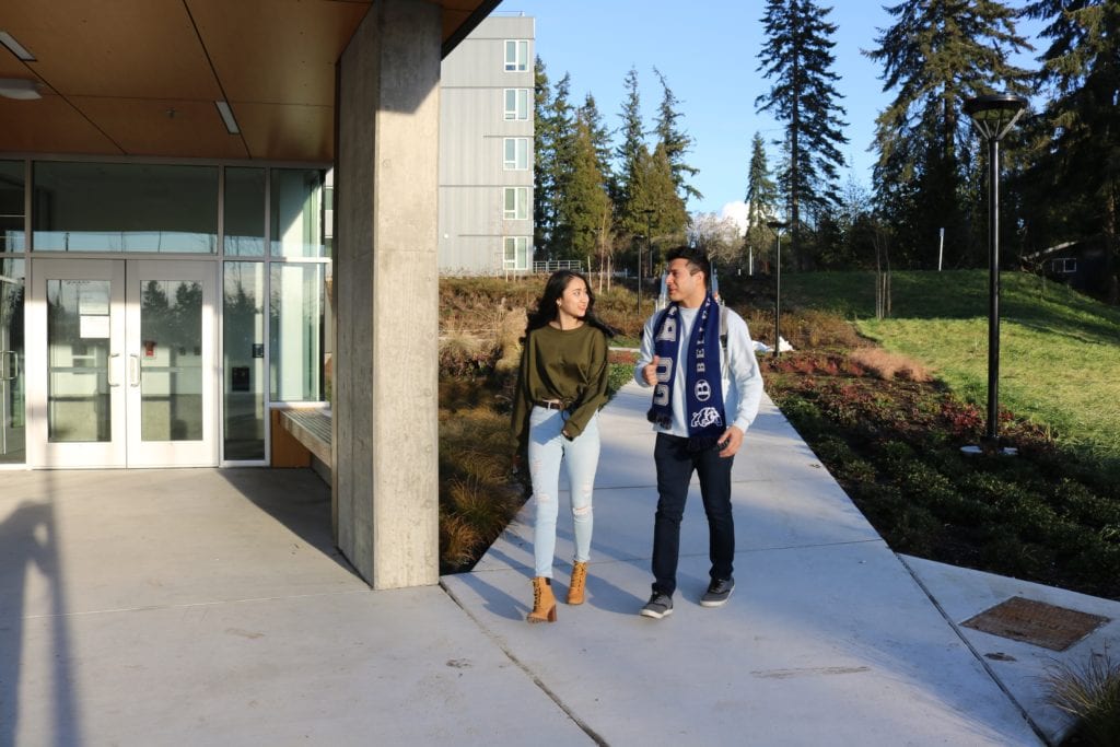 One female and one male student walking outside the residence hall