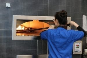 Worker pulling pizza out of oven