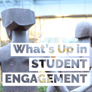 What's Up in Student Engagement - viewing the C Building from behind Ray Jensen's sculpture of students walking through the door of opportunity.