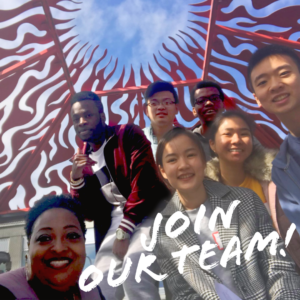 Join our team! Student workers pausing for a selfie under the flaming sculpture in the R Courtyard