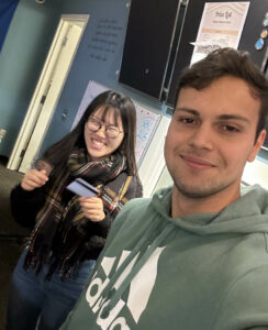 Two grinning students working at the Student Business Center front desk