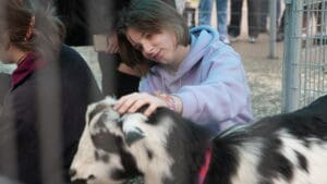 Student hanging out with a friendly black and white goat at the petting zoo.