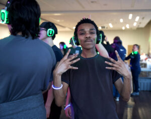 Student at CAB's Silent Beats Dance Party wearing glowing headphones and glowing arm band.