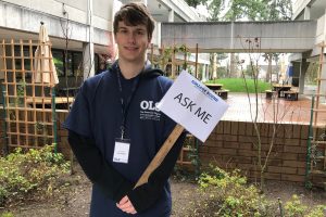 Student holding Ask Me sign