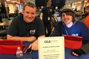 Students smiling behind OLS vendor booth