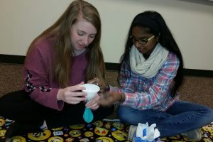 Two students fill stress ball balloons
