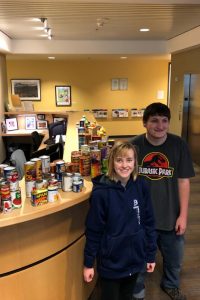 Two OLS Students pose with 128 canned food items at the North Campus front desk