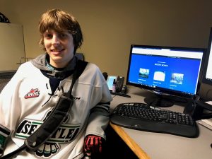 OLS Student sits in front of computer with his website over. 
