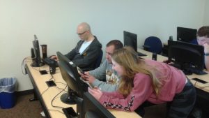 Students huddle around a computer screen to complete a group quiz