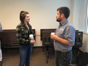 OLS Student smiles and talks with a visitor to the Coffee Social