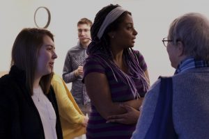 OLS Student smiles and talks with a visitor to the Coffee Social