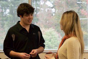 OLS Student smiles and talks with a visitor to the Coffee Social