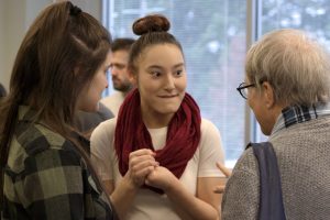 OLS Student smiles and talks with a visitor to the Coffee Social