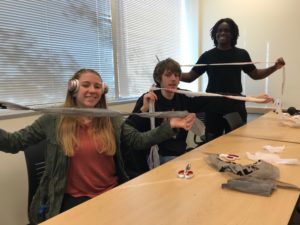 Three students hold up plarn they make in class