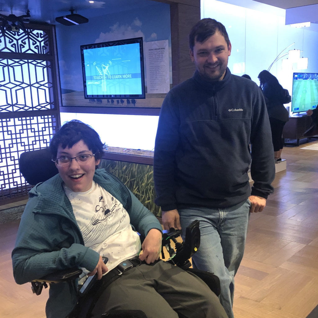 a young adult male student stands next to a young adult female student in a wheelchair at the Microsoft Visitor Center