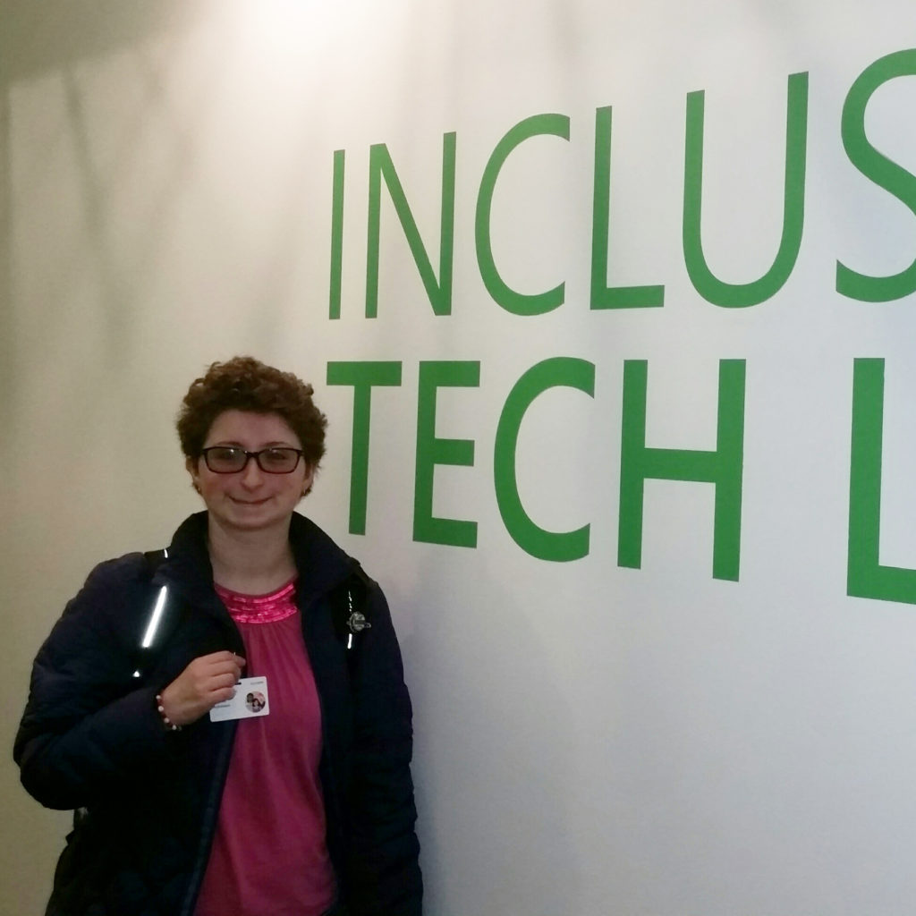 Student poses in front of Microsoft Inclusive Tech Lab wall mural