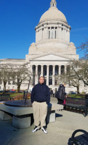 Young man stands in front ofWA State Capital building 