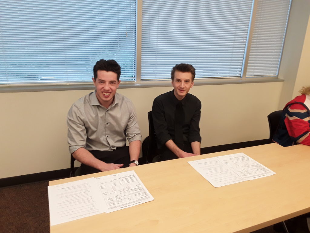 two male students dressed for job interviews sit at a desk