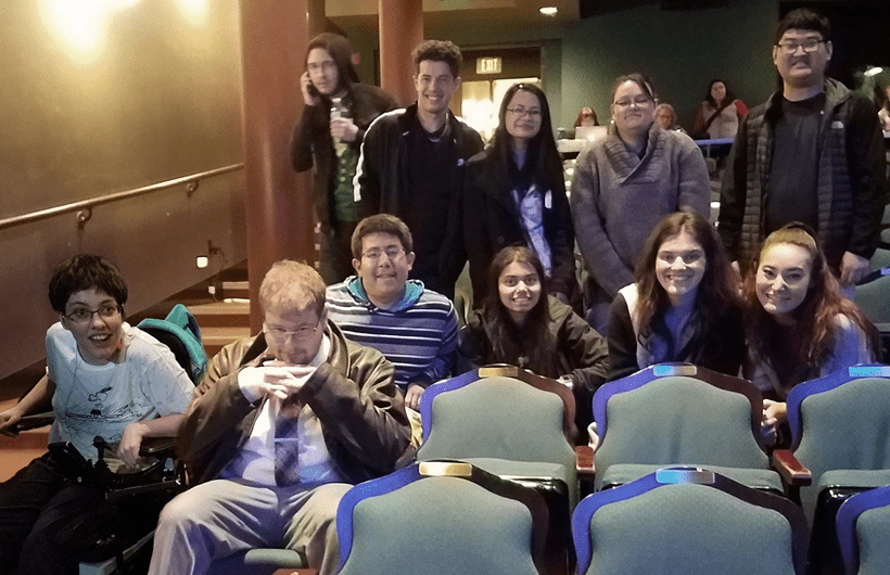 A group of students sit together in a theater. 