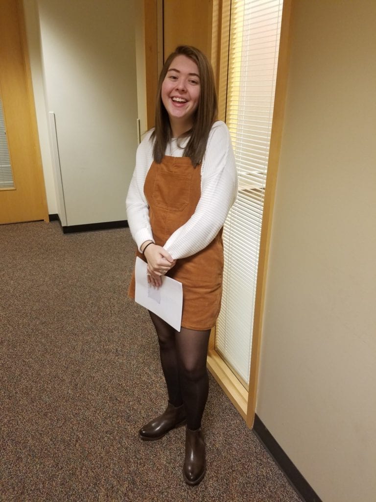 young adult woman stands in hallway dressed for job interview