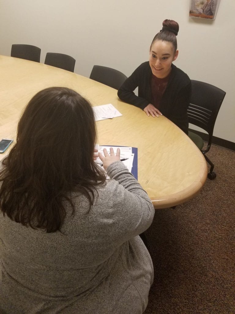 young adult woman sits across a table from a female interviewer at a  job interview