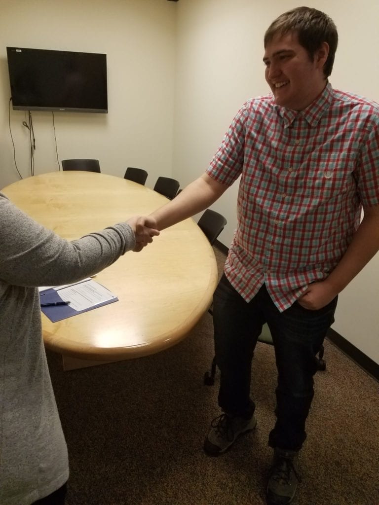 young adult male shakes hands with 