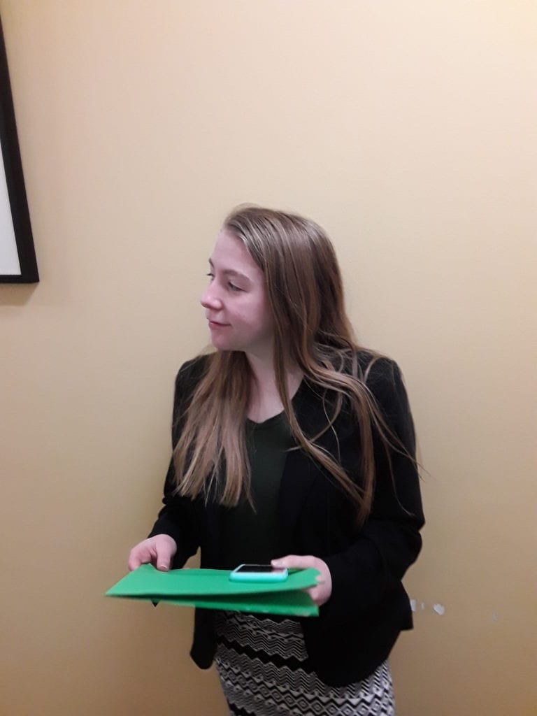 Professionally dressed young lady waits in hallway for interview