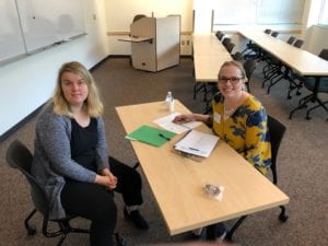 young woman and professional business woman sit at table and smile for camera