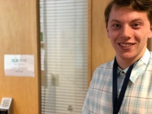 Young man smiles for camera in front of business office