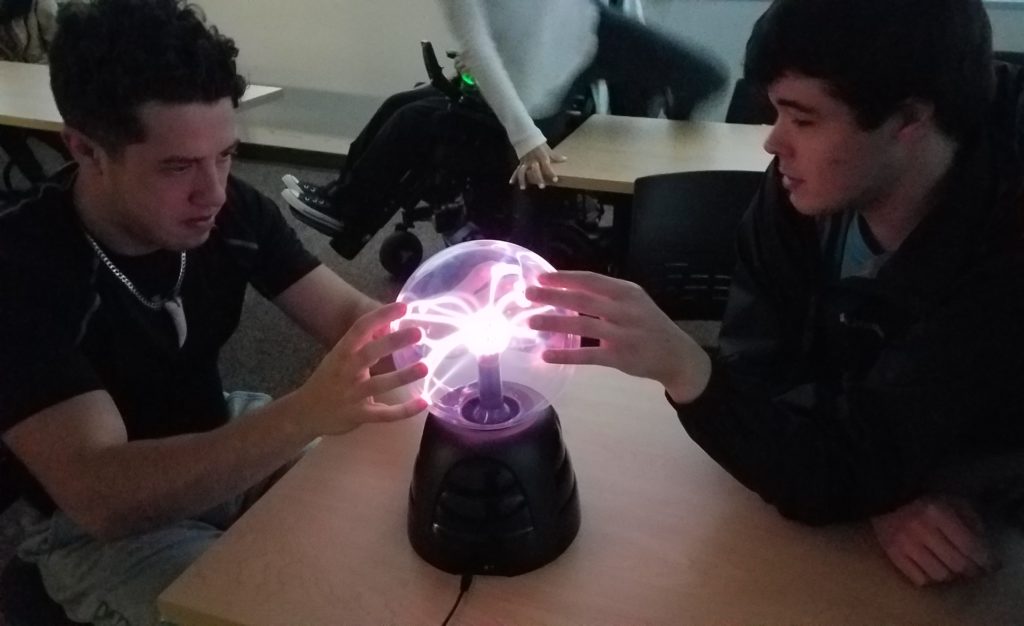 two students study a plasma lamp