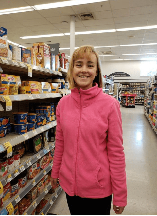 young woman stands in grocery store aisle smiling