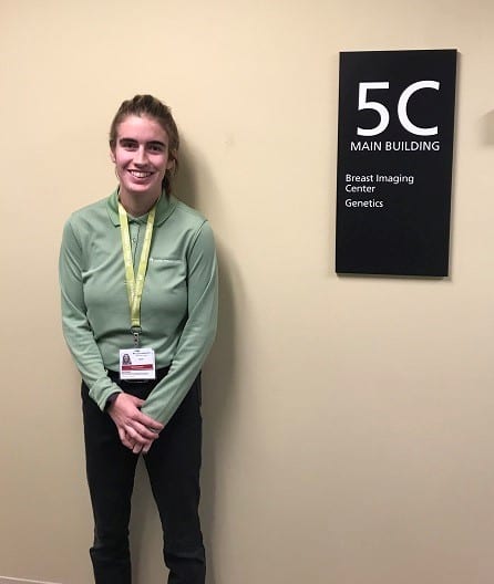 Young female stands by a sign at a hospital