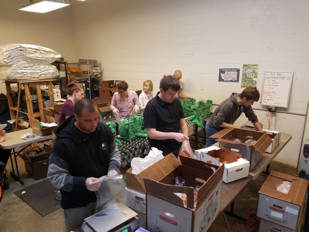 group of young adults fill produce bags with produce