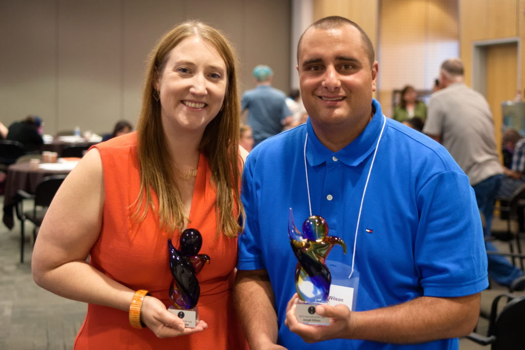 young man and woman holding awards