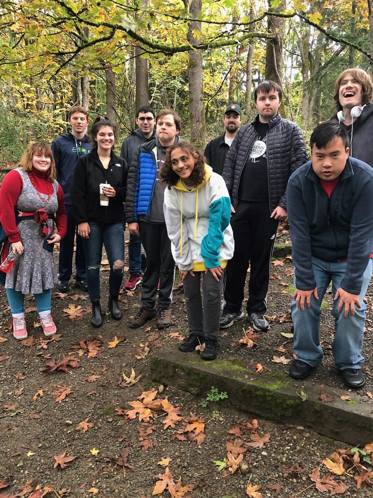 A group of young adults pose for a group photo in the woods