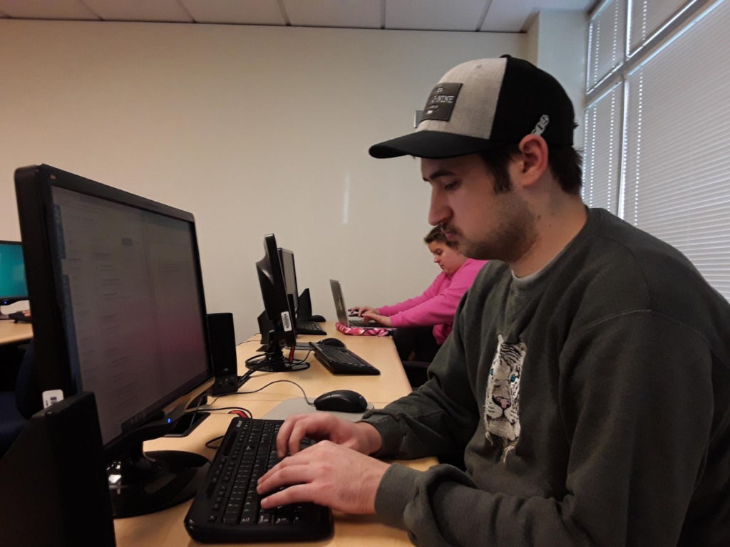 two young adults work at computers