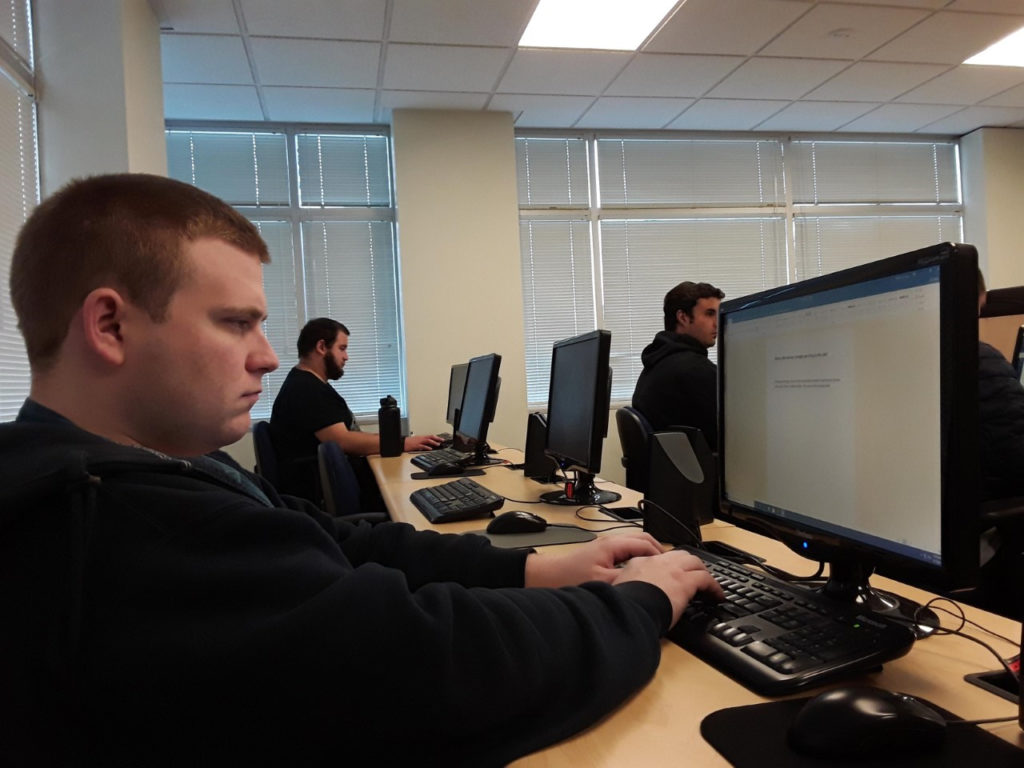 three young adult men work on computers 