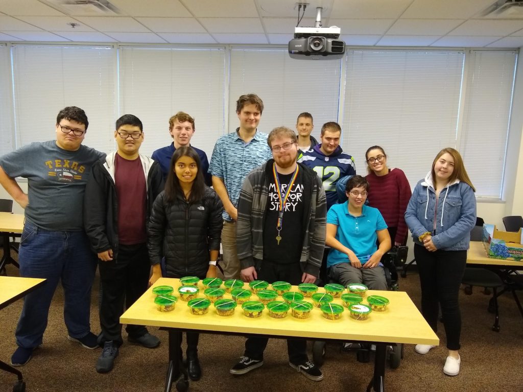 group of young adults pose for a group photo with containers of trail mix they made