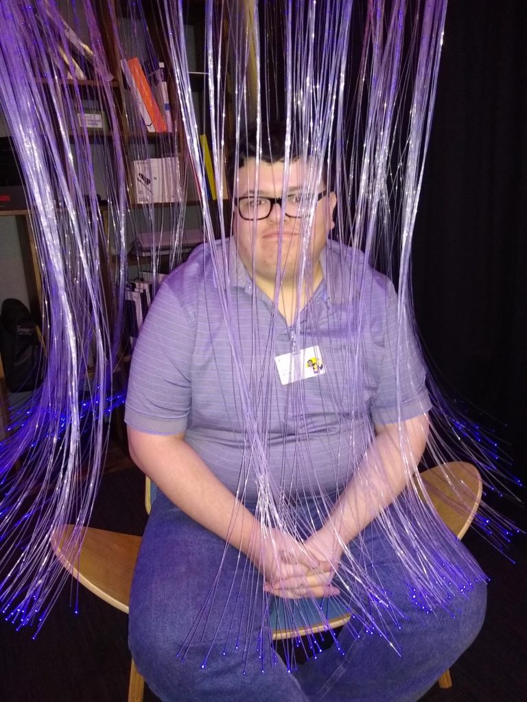 young adult man sits under jelly-fish like LED streamers