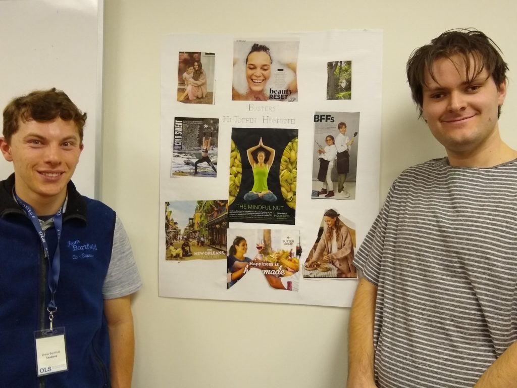 two young men pose with a collage of magazine photos