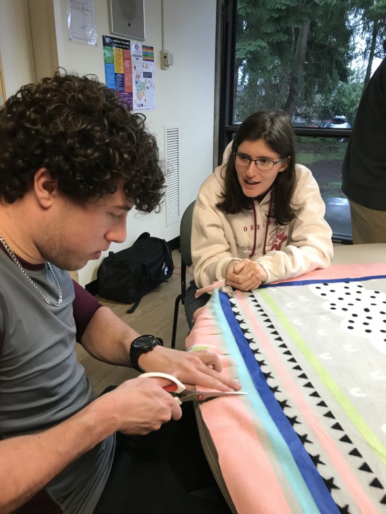 two young adults cutting fabric