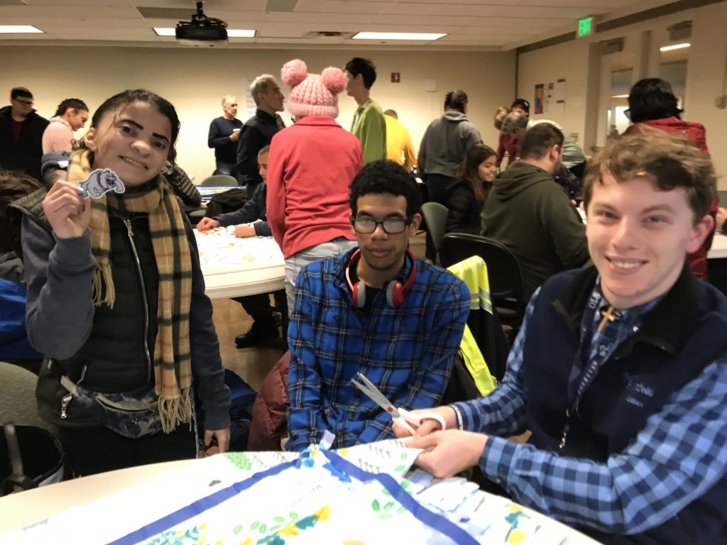 three young adults making blankets